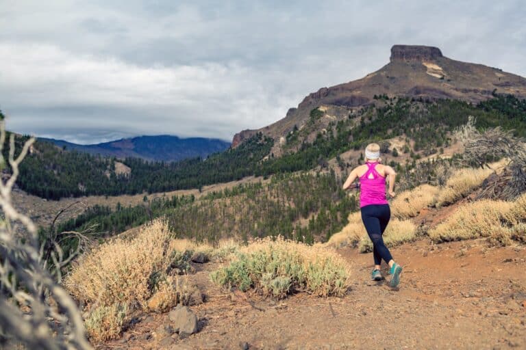 Trail running girl in mountains on rocky footpath cissn