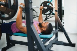 Weight lifter at the bench press lifting a barbell on an bench nasm cpt